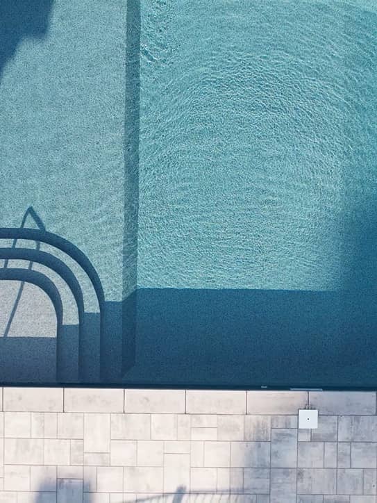 aerial-pool overhead shot of a pool with a stone staircase leading into clear blue water