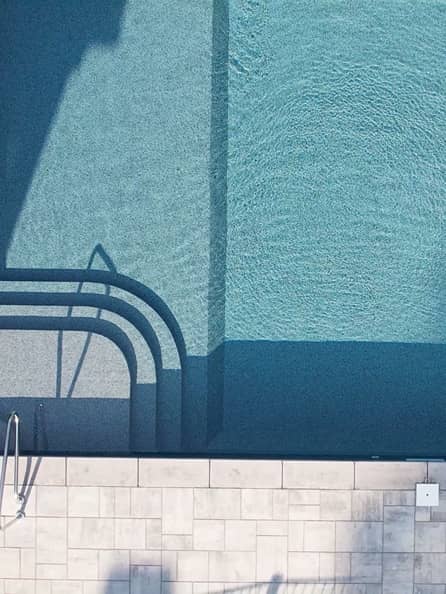 pool-stairs overhead shot of a pool with a stone staircase leading into clear blue water